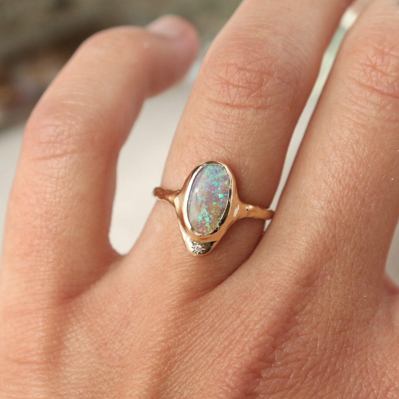 A long oval opal is bezel set in 14k gold  with  a star set  diamond at the base of the ring.