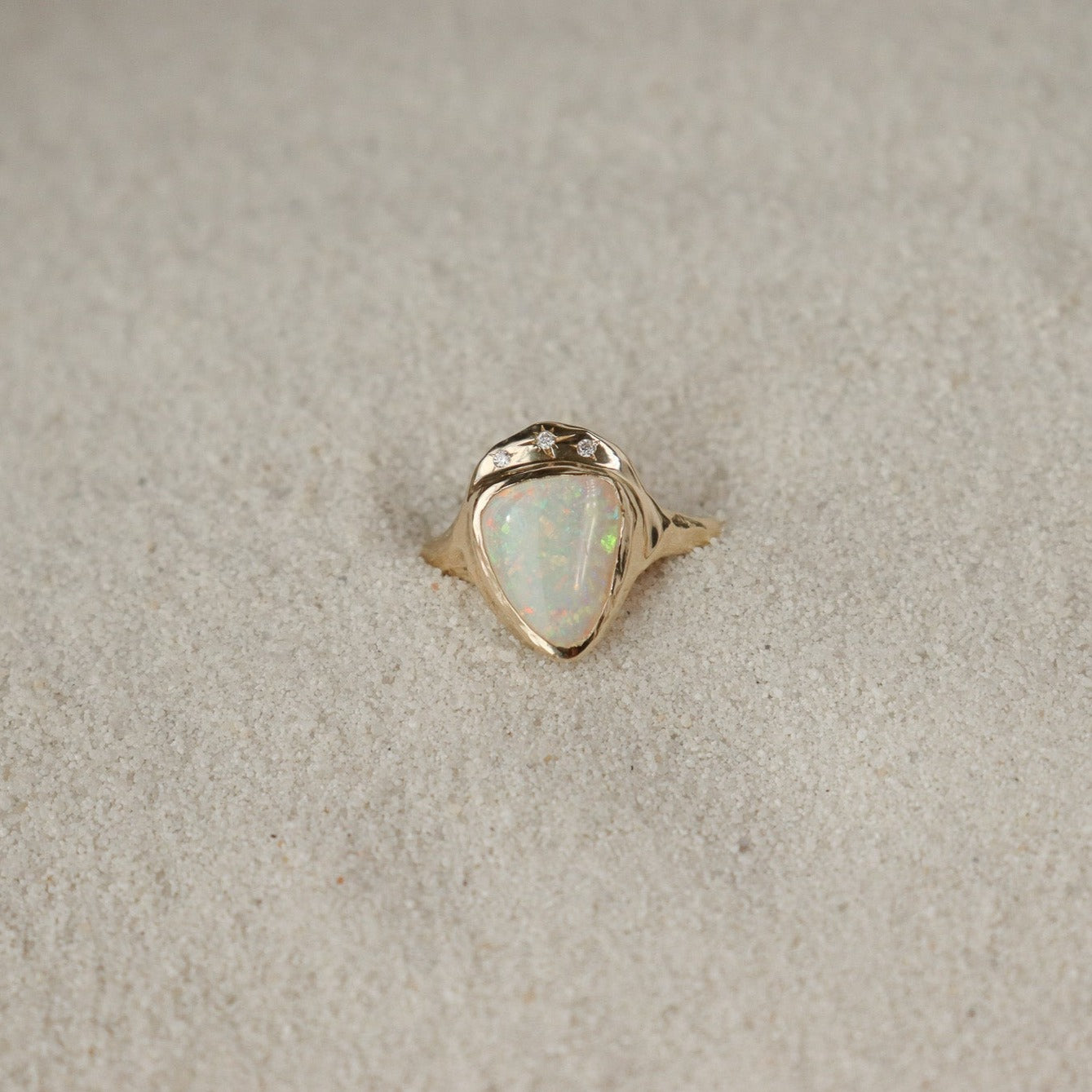 White triangle opal is bezel set in 14k gold with three star set diamonds.