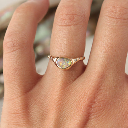A  crystal boulder opal is bezel set on an  organically crafted band with three star set diamonds on each side of the stone.