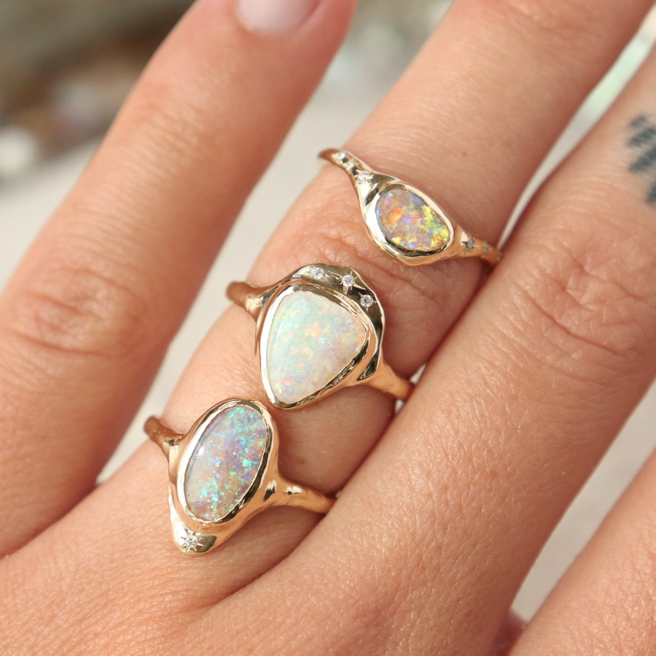 A stack of unique opal rings all set in 14k gold.