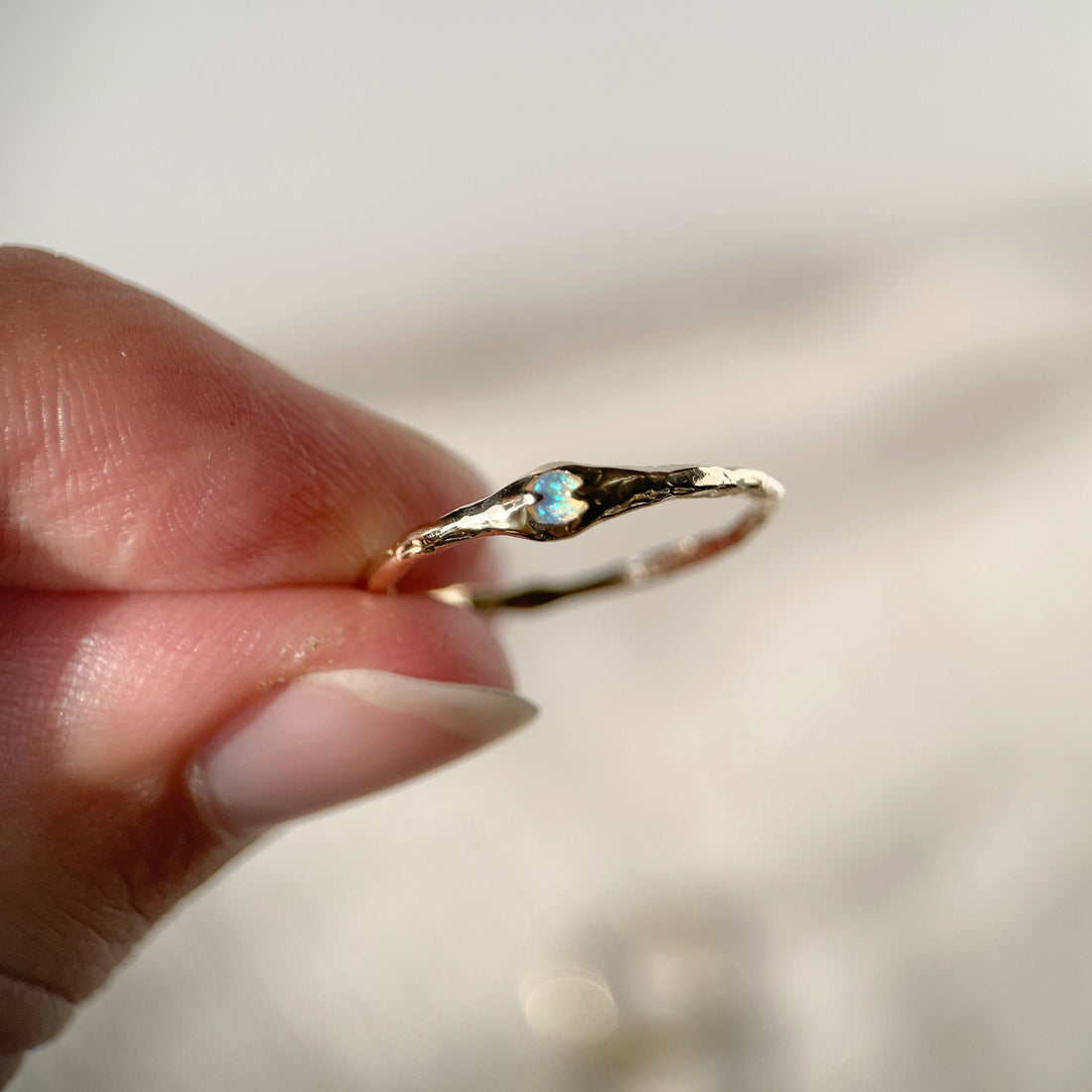 A tiny opal is prong set on a narrow 14k gold band.