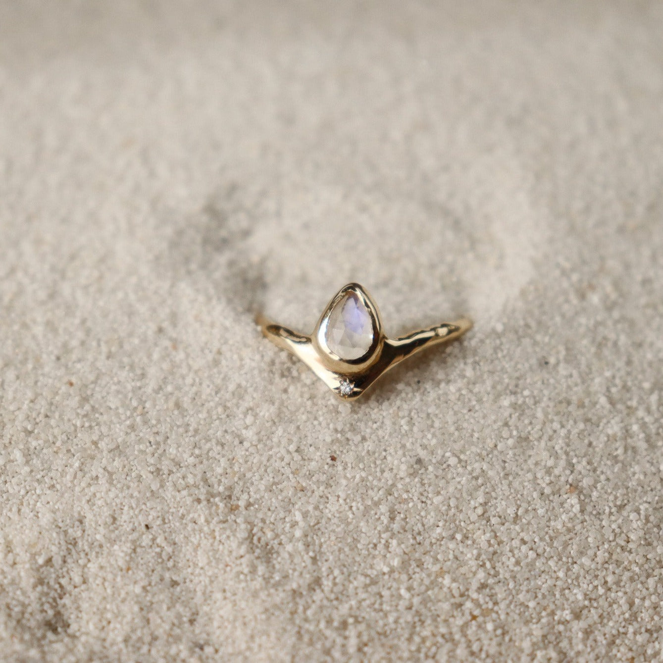 Pear-shaped moonstone, bezel-set with a dazzling diamond star positioned at the base for a celestial-inspired and enchanting jewelry design.
