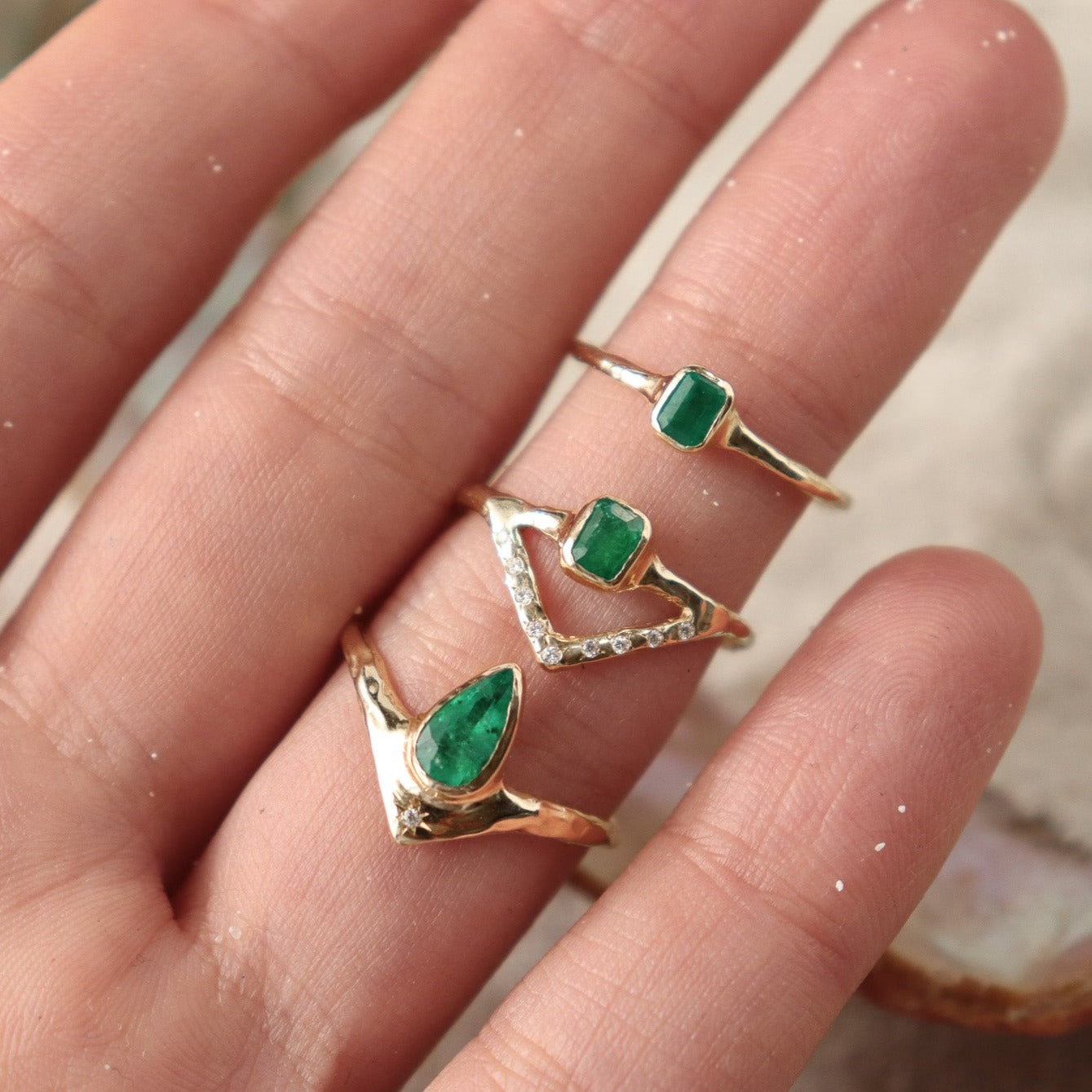 Three unique emerald rings shown together for comparison. 