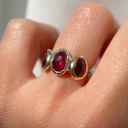 Three rose cut rhodolite garnets are bezel set  on an organically crafted 14k gold band.
