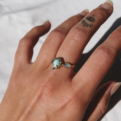 a gold flower variscite and opal ring is worn on a finger to show size
