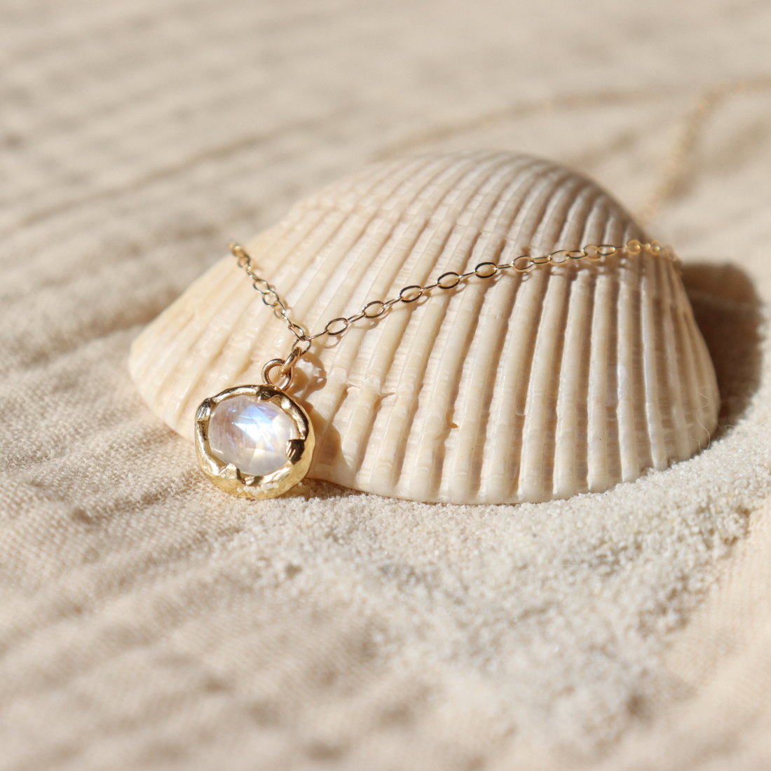 A rose cut moonstone is set in a gold setting and strung from a gold cable chain