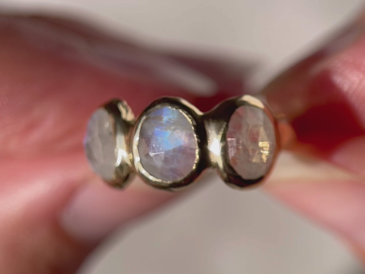 A close up video of three rose cut moonstones that are bezel set in 14k gold across the front of an organic band.