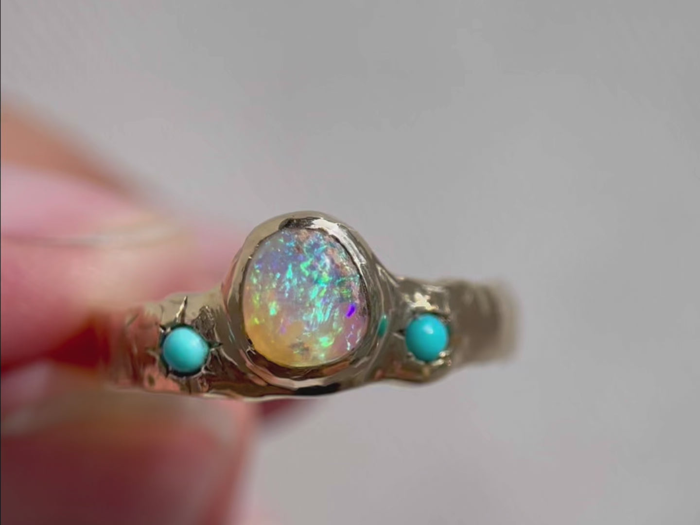 up close detail video of a wide gold band with a center opal and turquoise star settings