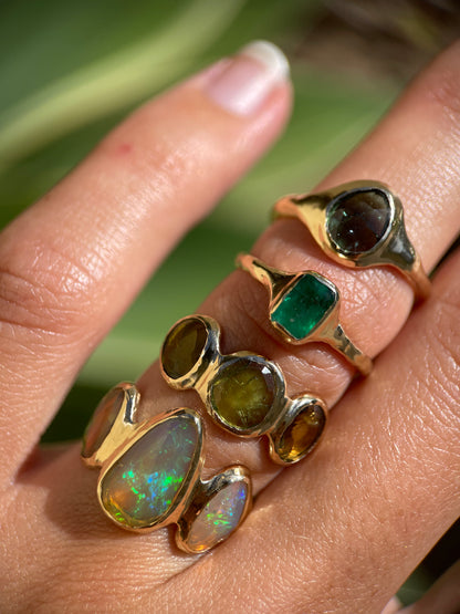 A stack of one of a kind green gemstone rings all set in 14k gold.