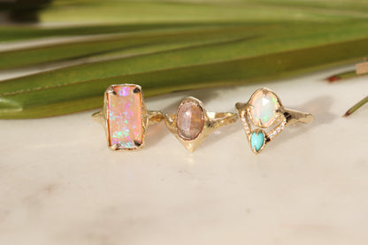 three gemstone rings displayed side by side on a marble table