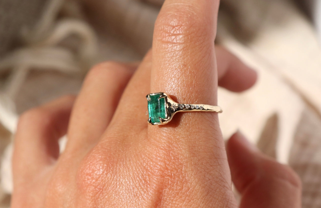 side view of a 14k gold emerald ring with diamond accents